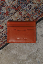 Brown leather cardholder on a textured surface