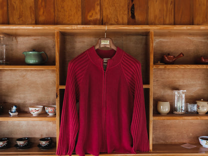 Red sweater on a hanger against a wooden shelf with various items