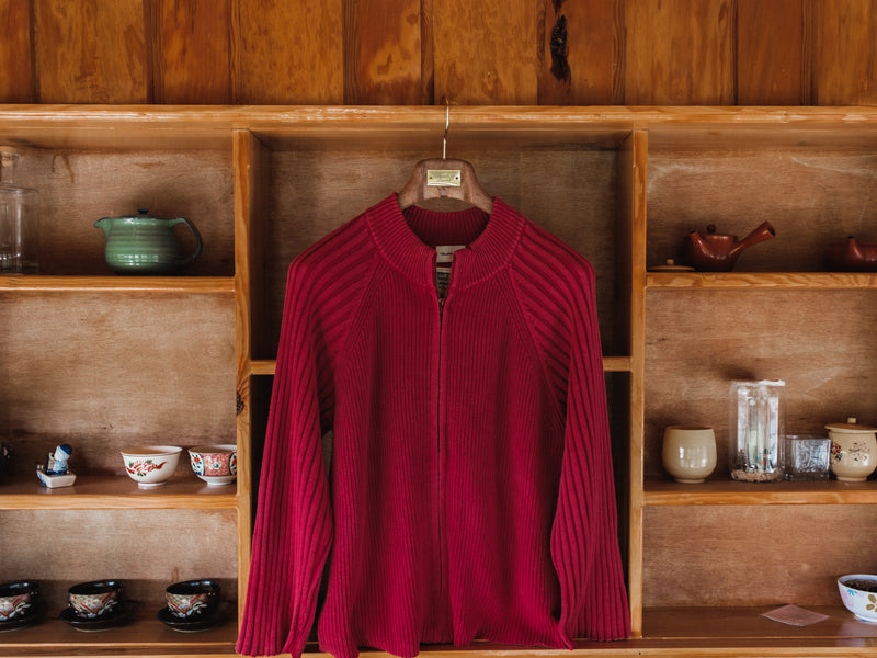 Red sweater on a hanger against a wooden shelf with various items