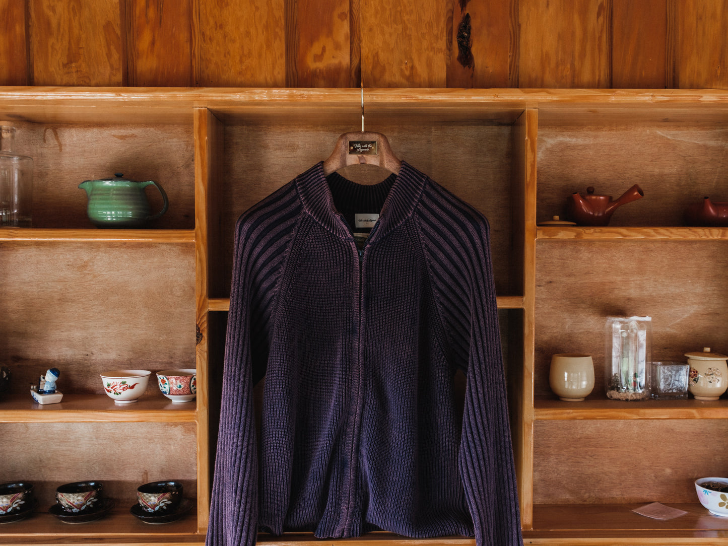Purple jacket hanging on a wooden shelf with various items