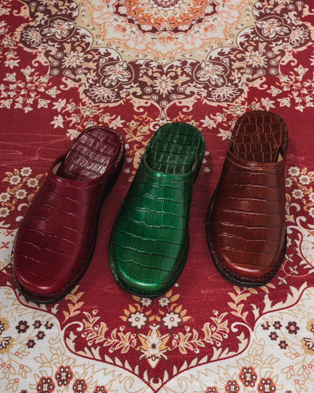 Three shoes in red, green, and brown on a patterned fabric background